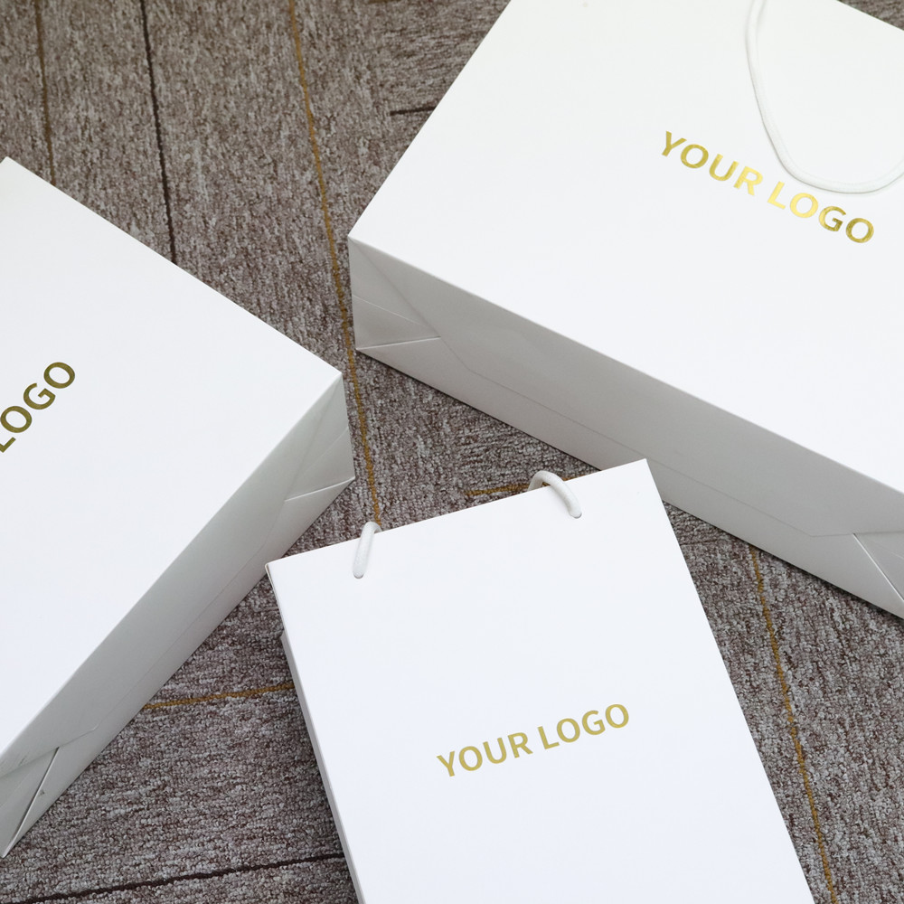 Borse per la spesa personalizzate abbigliamento logo stampato in oro design sacchetti di imballaggio in carta di cartone bianco per la vendita al dettaglio